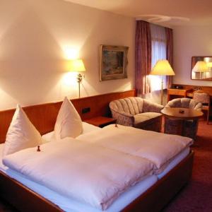 バート・ウーラッハにあるHotel Buckの大きなベッドと椅子が備わるホテルルームです。