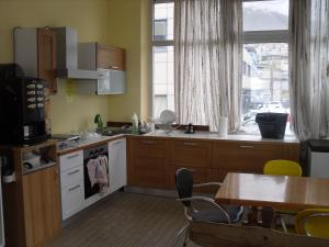 cocina con armarios de madera, mesa y ventana en Hostel San Marino, en San Marino