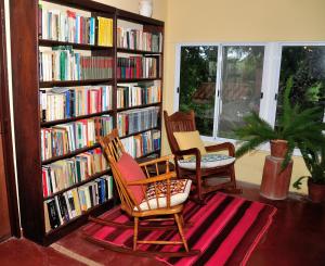 a library with two chairs and bookshelves filled with books at Finca Cielo Verde in Chicoana