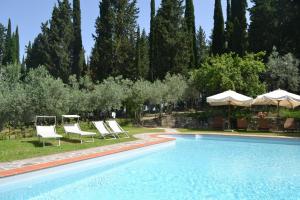 una piscina con tumbonas, sombrillas y árboles en Tenuta Poggio ai Mandorli, en Greve in Chianti