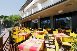 a group of yellow tables and chairs outside a restaurant at Hotel Genzianella in Cervia
