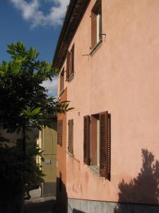 a building with brown shuttered windows and a tree at Casa "Le tre Muse" in Deruta