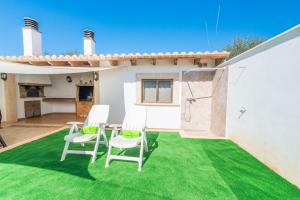 a patio with green grass and white chairs at Ca Na Dora in Santanyi