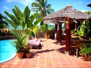 a patio with a umbrella and a swimming pool at Vila Da Lua in Jacumã