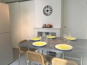 uma sala de jantar com uma mesa com cadeiras e um relógio em Maison de vacances à Dieppe em Dieppe