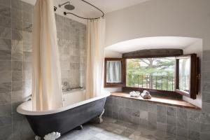 a bath tub sitting next to a window in a bathroom at Relais Villa Belpoggio - Residenza D'Epoca in Loro Ciuffenna