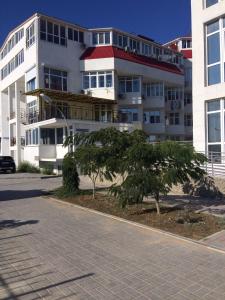 un edificio de apartamentos con un árbol delante de él en KafaLux en Feodosiya