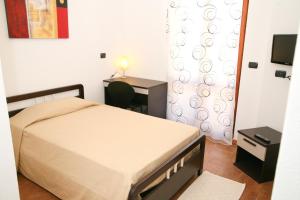 a bedroom with a bed and a desk and a television at Villa Marogna in Alghero