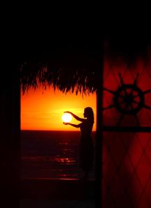 a woman standing in front of a window with the sunset at Casa Gonzales Gonzales in Canoas de Punta Sal