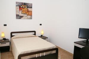 a bedroom with a bed and two night stands and a television at Villa Marogna in Alghero