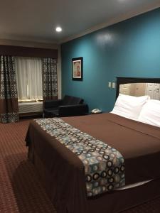 a hotel room with a bed and a chair at Scottish Inns & Suites Timber Creek, Houston, TX in Houston