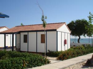 uma casa branca com um telhado vermelho ao lado da praia em Orbitur Ilha de Armona em Olhão