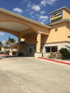 a building with a sign for a shopping center at Scottish Inns & Suites Timber Creek, Houston, TX in Houston