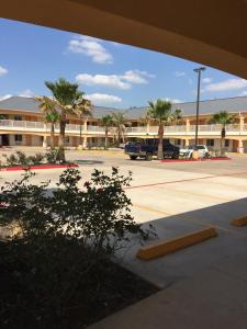 a parking lot in front of a building with palm trees at Scottish Inns & Suites Timber Creek, Houston, TX in Houston