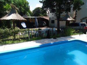 a swimming pool in a yard with a fence and umbrellas at Hosteria Zure-Echea in Valle Hermoso