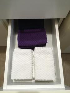 Maison l'héritage في لأنسي سانت جين: رف به ثلاث مناشف بيضاء ومنشفة أرجوانية