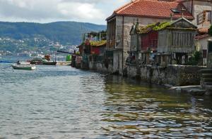 a small boat in a river next to buildings at Apartamentos Granxola in Sanxenxo