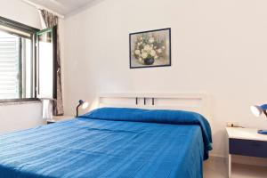 Un dormitorio blanco con una cama azul y una ventana en Appartamento Monte Oro, en Santa Maria Navarrese
