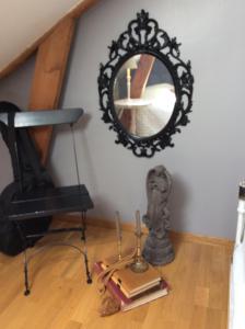 a mirror on a wall with a chair and a book at Gothenburg View Apartment in Gothenburg