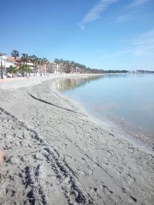 una playa con huellas en la arena y el agua en Apartamentos Espejo, en Los Alcázares