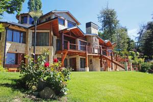 a large house on a grassy yard with flowers at Bahia Paraiso Luxury Suites Boutique Hotel in San Carlos de Bariloche