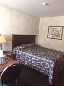um quarto de hotel com uma cama e uma secretária com uma cadeira em Fair Motel em Upper Saddle River