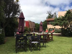 a table and chairs with umbrellas in a yard at Villa Olimpia Cabañas in Villa Gesell