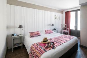 una camera da letto con un letto con un cappello sopra di Hôtel de La Marée - Face à l'océan - Ile de Ré a Rivedoux-Plage