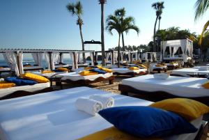 una fila di letti su una spiaggia con palme di Lifestyle Crown Residence Suites a San Felipe de Puerto Plata