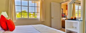 a bedroom with a bed with red pillows and a window at Lifestyle Crown Residence Suites in San Felipe de Puerto Plata