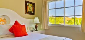 a bedroom with a bed with a red pillow and a window at Lifestyle Crown Residence Suites in San Felipe de Puerto Plata