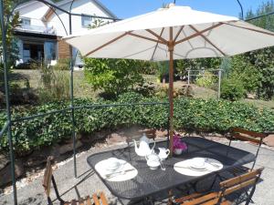 - une table avec un parasol, des assiettes et de la vaisselle dans l'établissement Chambres d'Hôtes Rachelle Schneider, à Husseren-les-Châteaux
