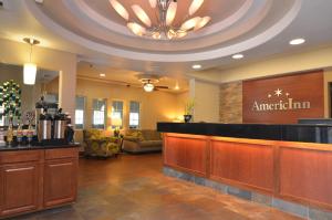 a lobby of an american inn with a bar at AmericInn by Wyndham Des Moines Airport in Des Moines
