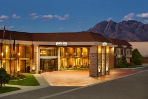 a large building with mountains in the background at Park Inn by Radisson Salt Lake City -Midvale in Midvale