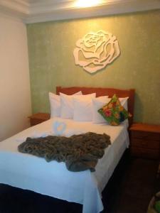 a bedroom with a white bed with a painting on the wall at Hotel Pousada Recanto in Ilha Comprida