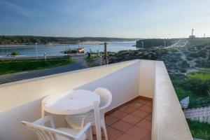 a table and chairs on a balcony with a view of the water at Apartamentos Dunamar in Vila Nova de Milfontes