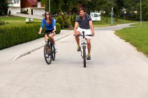 two people riding bikes down a road at Apartments Beeland Skok in Mozirje