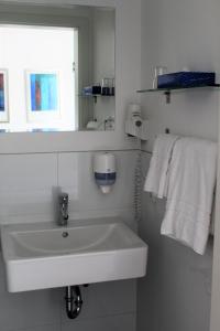 uma casa de banho branca com um lavatório e um espelho em Hotel & Restaurant Hüllen em Barweiler
