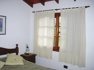 1 dormitorio con 1 cama y una ventana con cortinas en Cabañas El Maiten en San Clemente del Tuyú