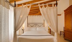a bedroom with a canopy bed with white curtains at Casal Santa Eulalia in Can Picafort