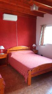 1 dormitorio con cama de madera y pared roja en Samana Holiday, en Carpintería