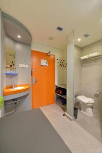 uma casa de banho com uma porta laranja, um lavatório e um WC. em POP! Hotel Timoho Yogyakarta em Yogyakarta