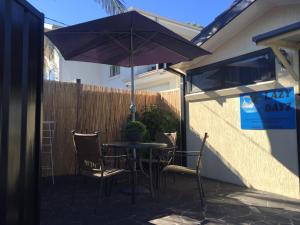 
a patio area with a table, chairs and umbrella at Lazy Dayz Shellharbour in Shellharbour
