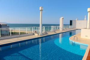 a swimming pool with a view of the ocean at Aquarelle Ingleses in Florianópolis