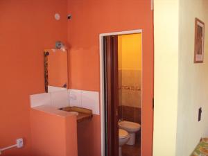 an orange bathroom with a toilet and a sink at Cabañas del Molle in Valle Hermoso +6 photos