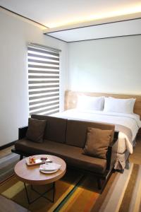 a bedroom with a bed and a couch and a table at Allstay Ecotel Yogyakarta in Yogyakarta