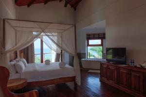 a bedroom with a bed and a television and a tub at Cardamon Hotel Nilaveli in Nilaveli
