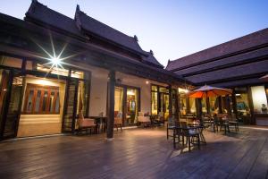 an outdoor patio with tables and chairs and an umbrella at Sibsan Luxury Hotel Rimping in Chiang Mai