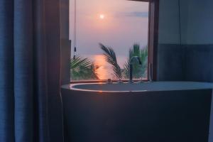 a bathroom with a tub and a window with the sunset at Cardamon Hotel Nilaveli in Nilaveli