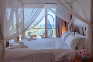 a bedroom with a white bed with a window at Cardamon Hotel Nilaveli in Nilaveli